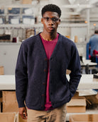 Person wearing a navy cardigan over a red t-shirt in an indoor setting with boxes and furniture.