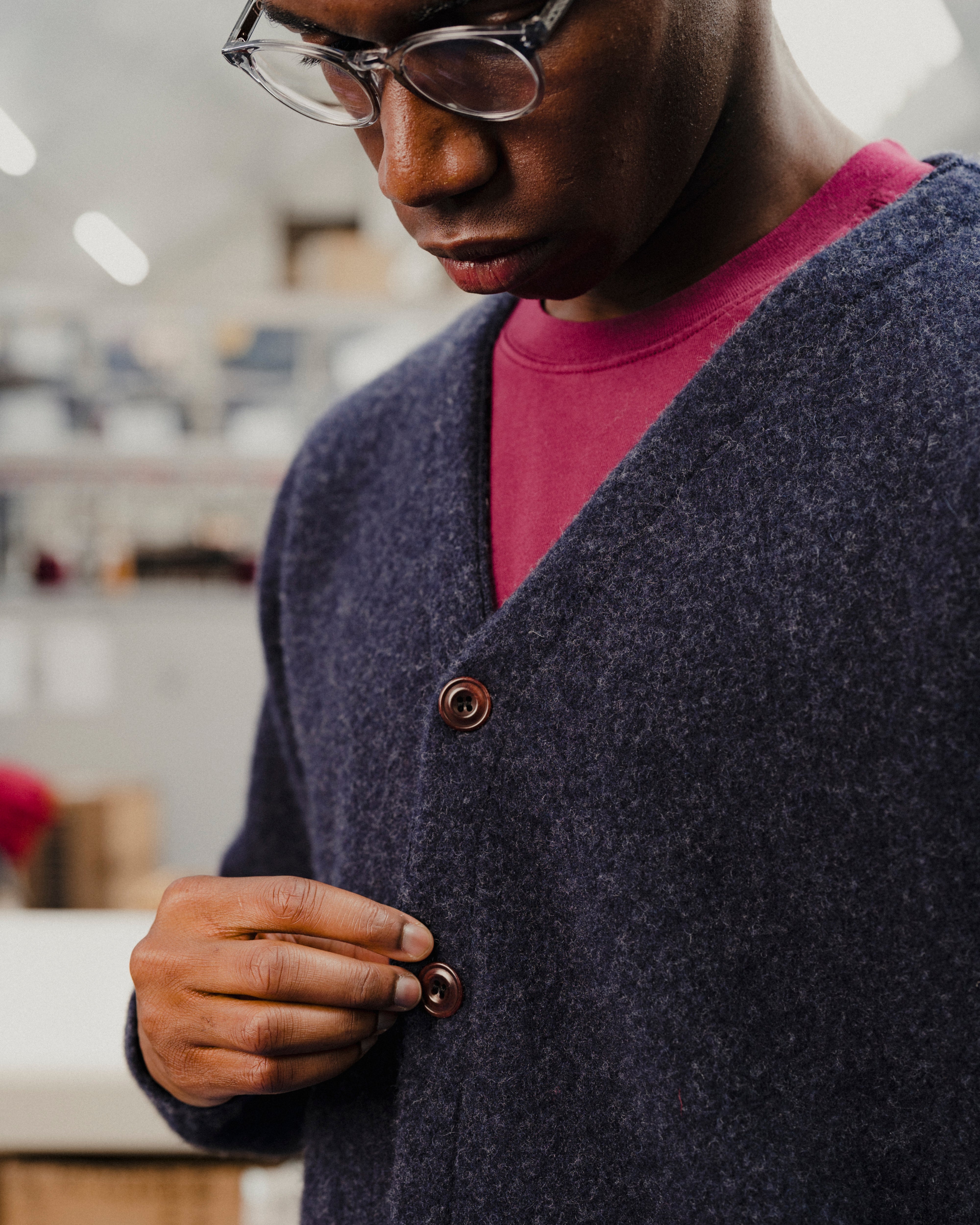 Person wearing a navy cardigan with a blurred indoor background
