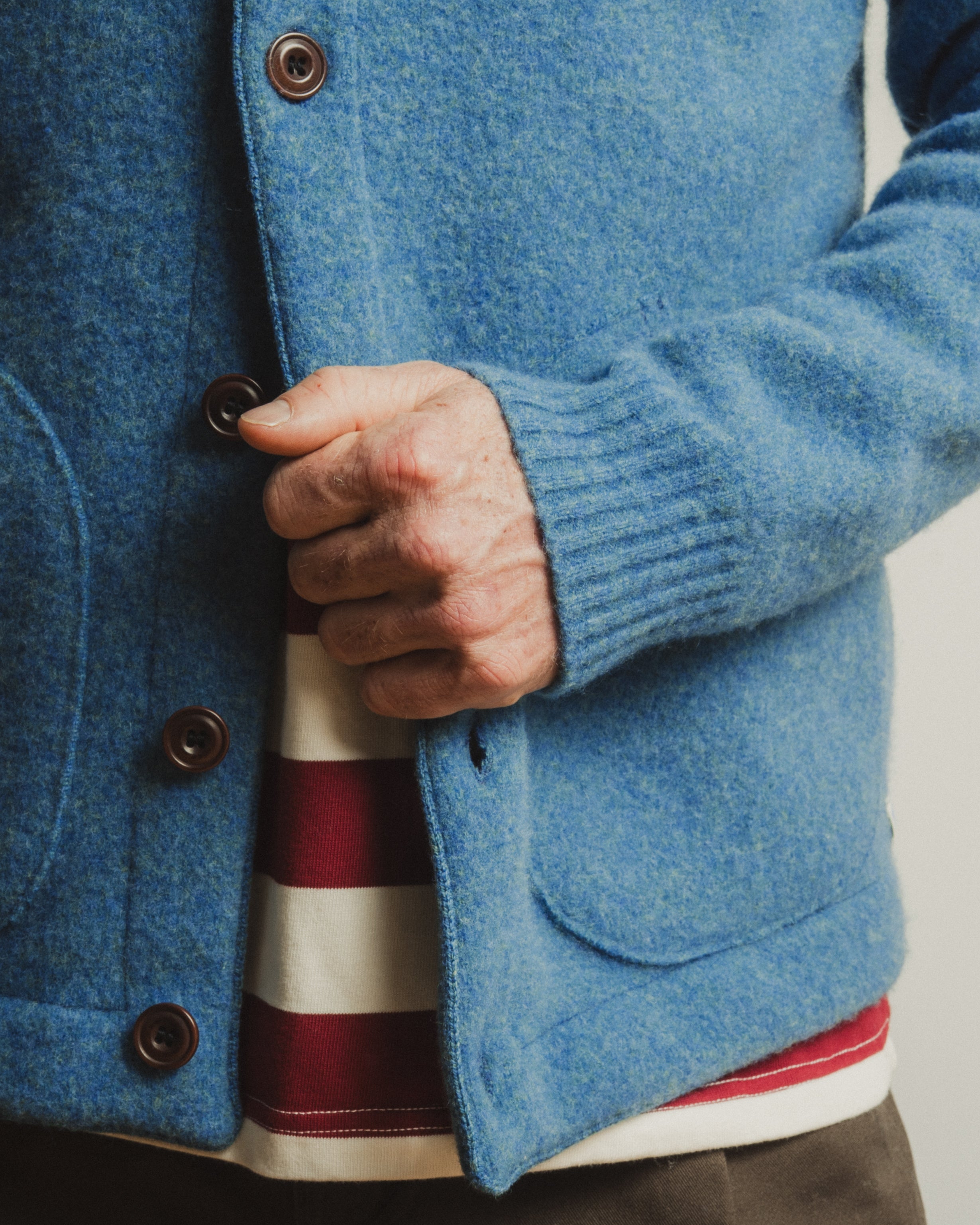 Close-up of a person wearing a blue jacket with a striped shirt underneath.