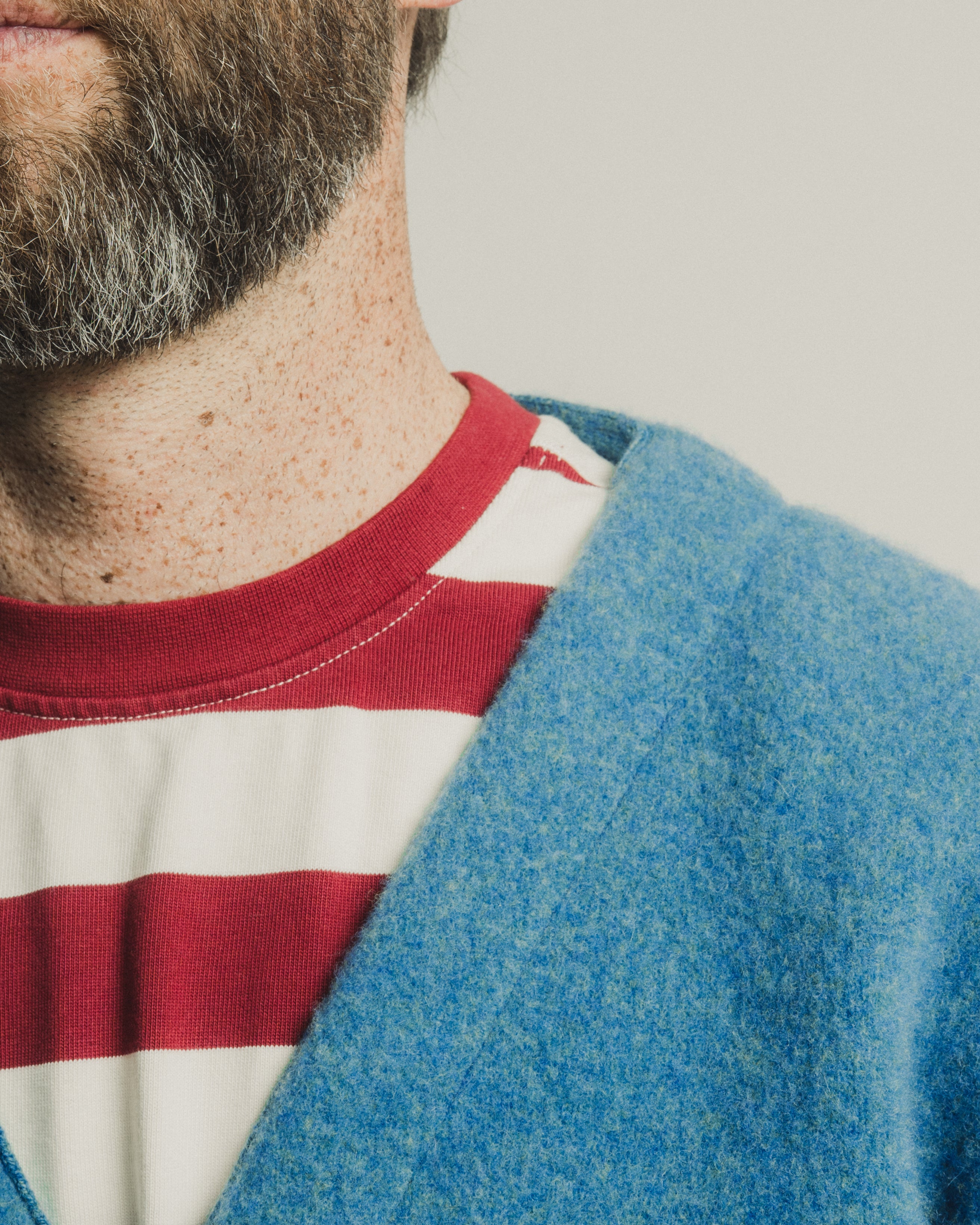 Person wearing a blue cardigan over a red and white striped shirt