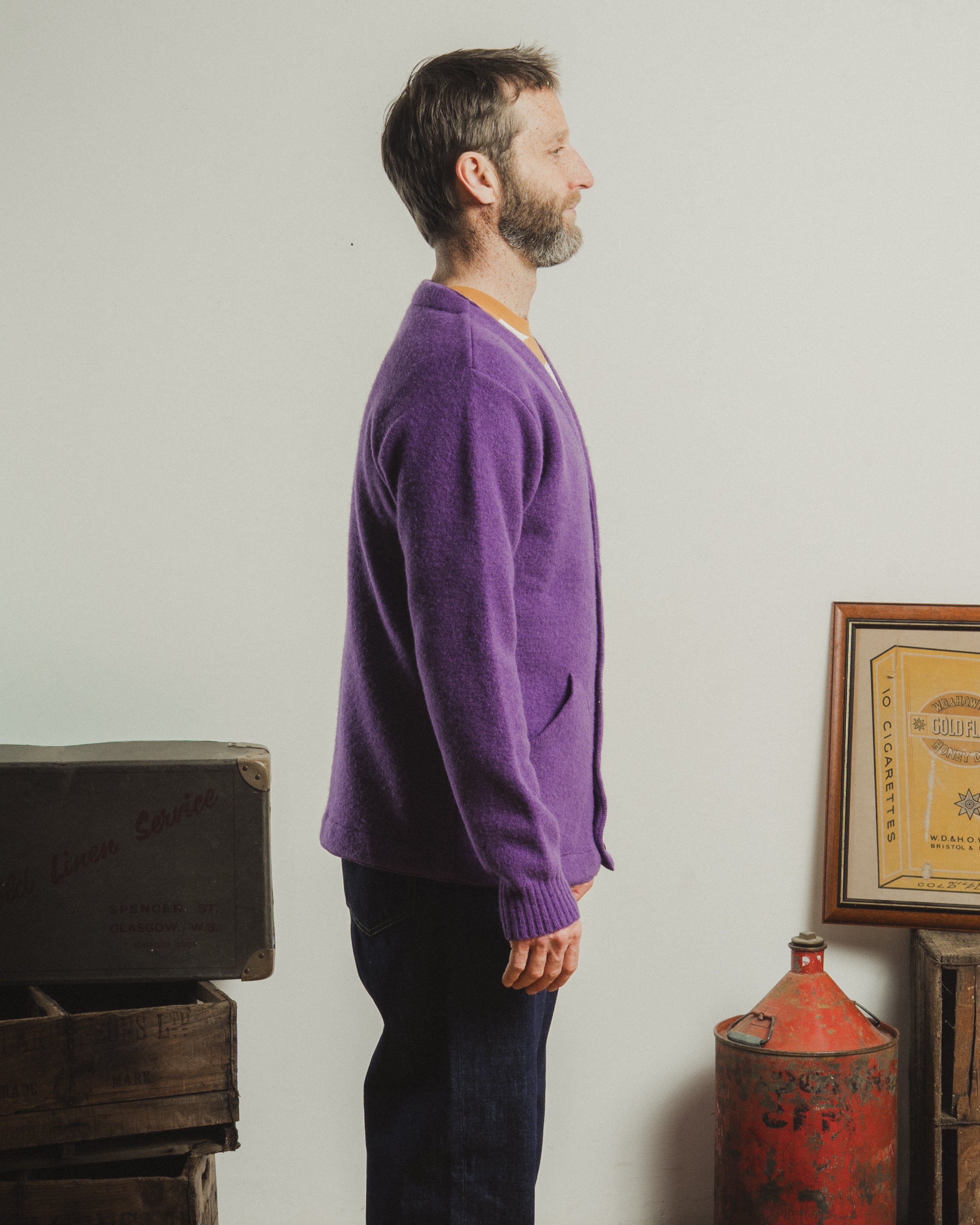 Man wearing a purple sweater standing in a room with vintage items.