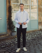 Man standing on a cobblestone street in front of a building with a light blue door.