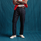 Person wearing dark jeans and a red jacket against a blue background