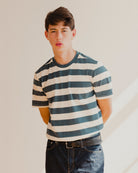 Person wearing a blue and white striped shirt and jeans against a plain background