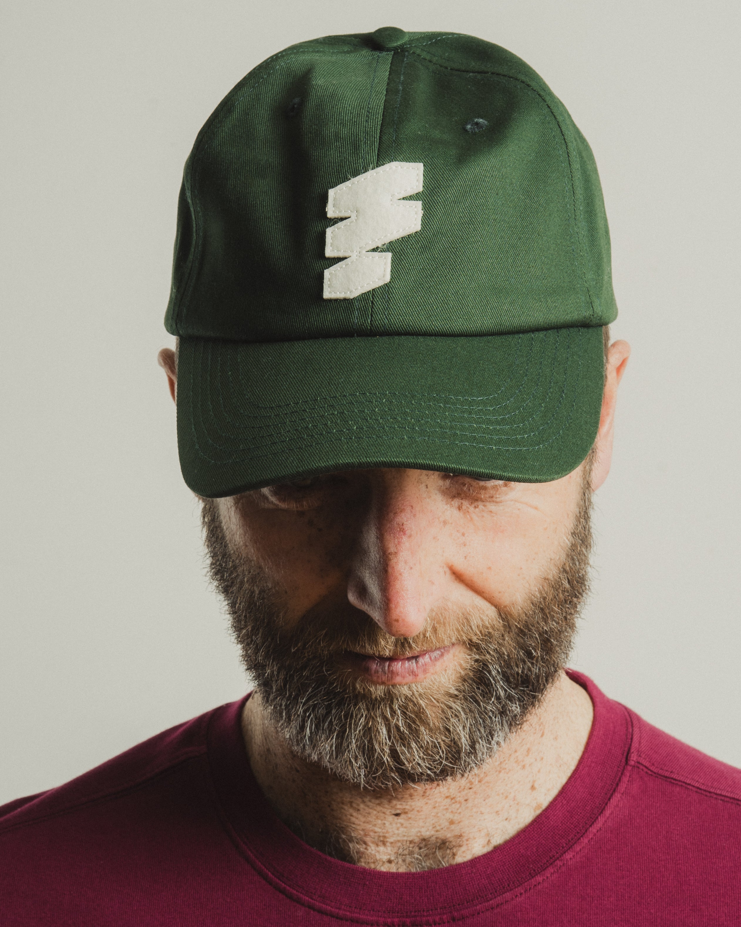 Person wearing a green cap with a logo on a plain background