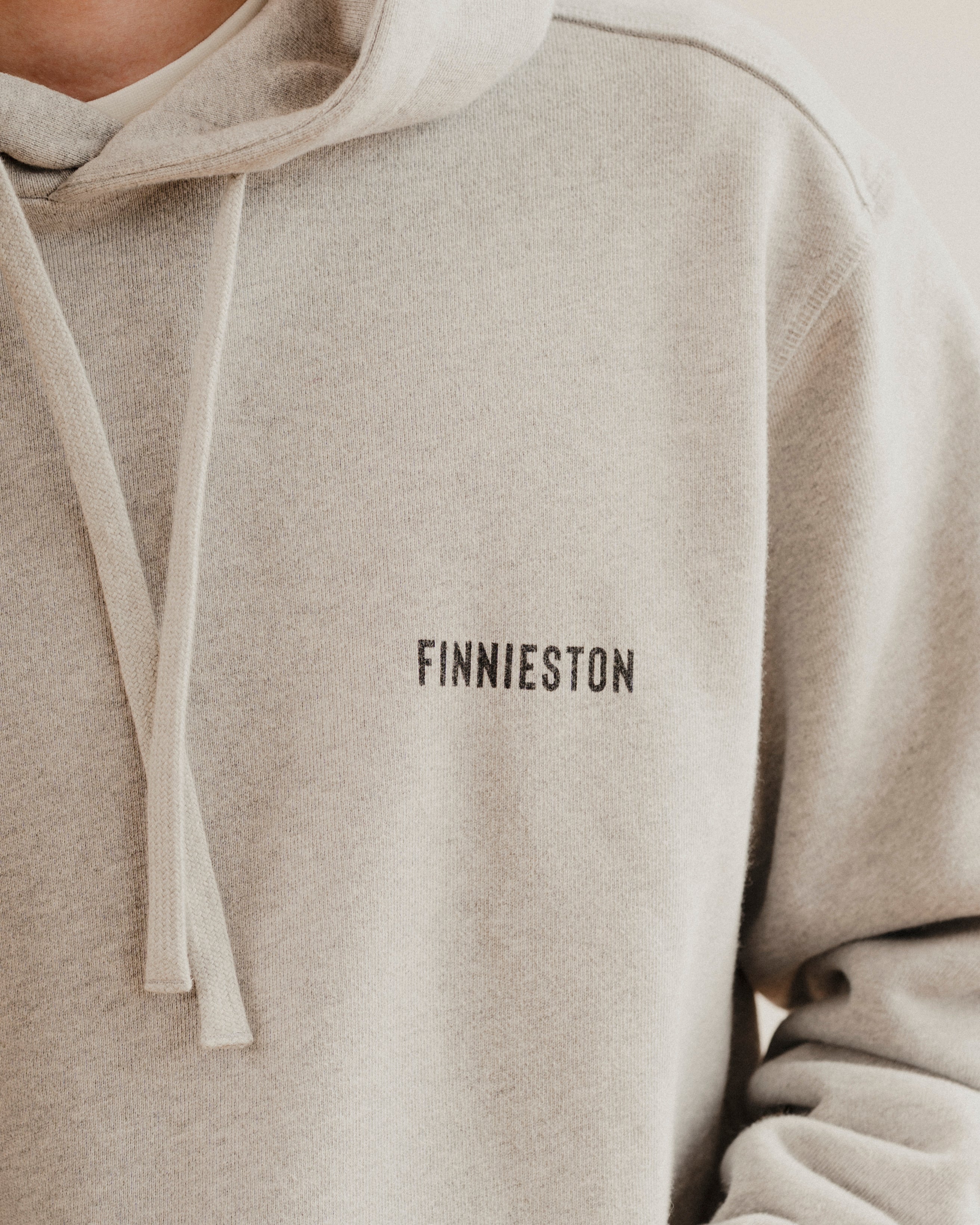 grey hoodie with 'FINNIESTON' text on a plain background