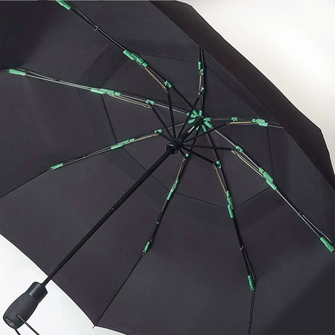 Black umbrella with green accents on a white background