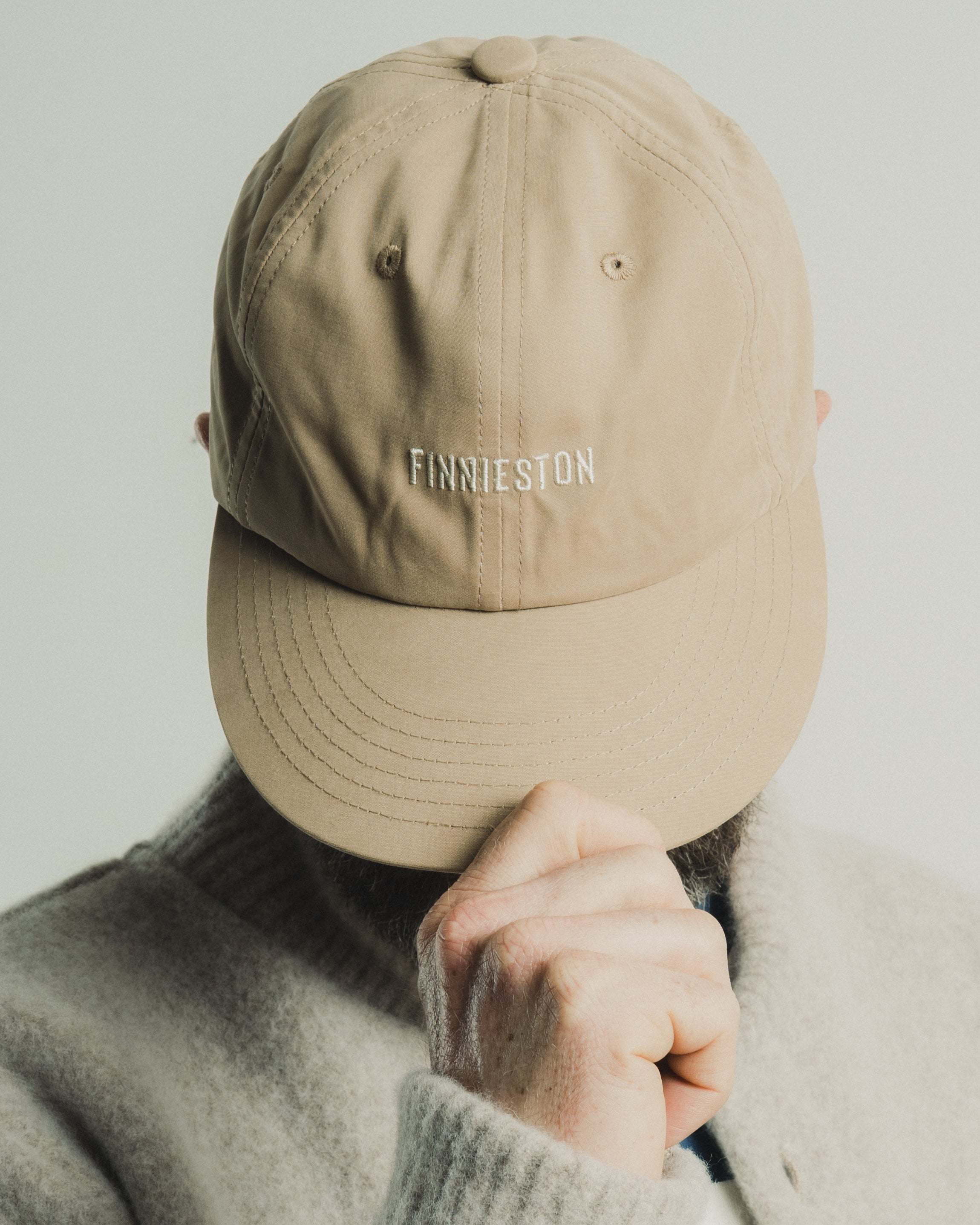 Beige cap with 'Finnieston' text worn by a person against a plain background