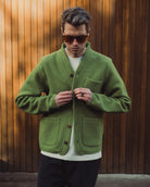 Man wearing a green cardigan against a wooden background