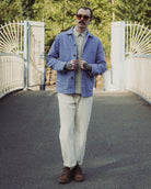 Man wearing a blue jacket and sunglasses standing on a bridge