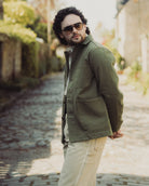 Man wearing a green jacket and sunglasses on a blurred street background