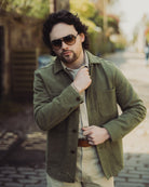 Man wearing a green jacket and sunglasses on a blurred street background