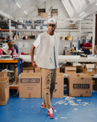 Man wearing a light grey vest and a white t-shirt in a warehouse setting