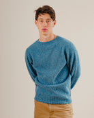 Man in a blue wool knit sweatshirt crewneck on a plain white background