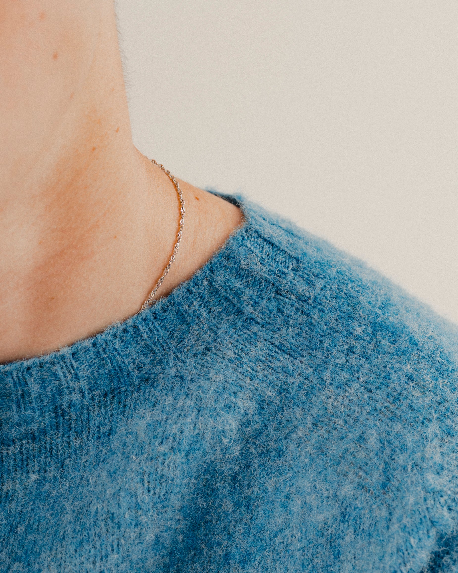 Close up on a blue wool knit crewneck sweatshirt jumper focused on the neckline with a plain background