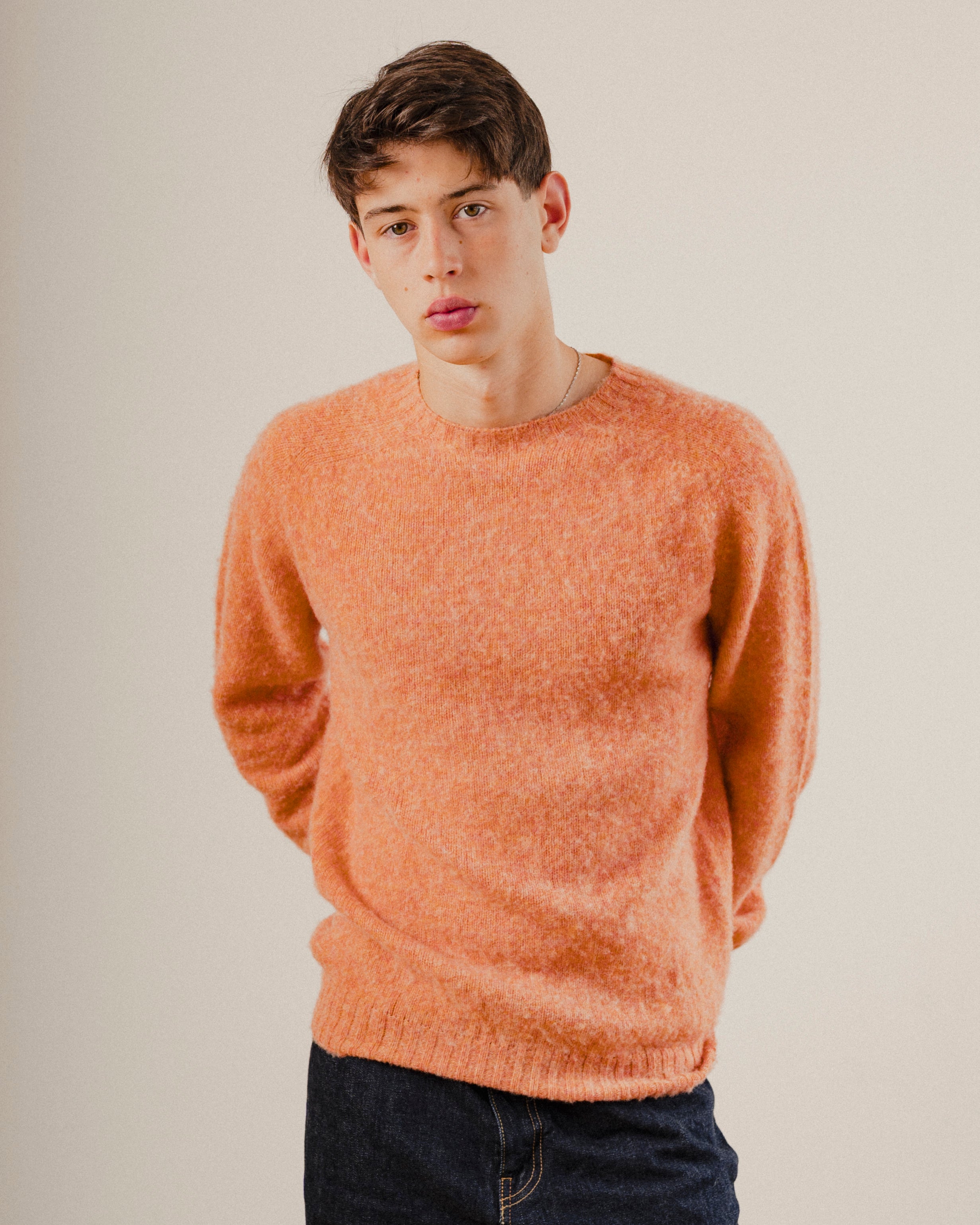 Man in an orange wool knit sweater crewneck jumper on a plain white background