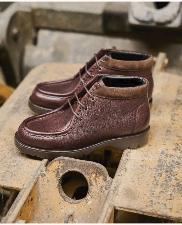 Pair of brown leather Kleman boots on a rustic metal surface