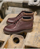 Pair of brown leather Kleman boots on a rustic metal surface
