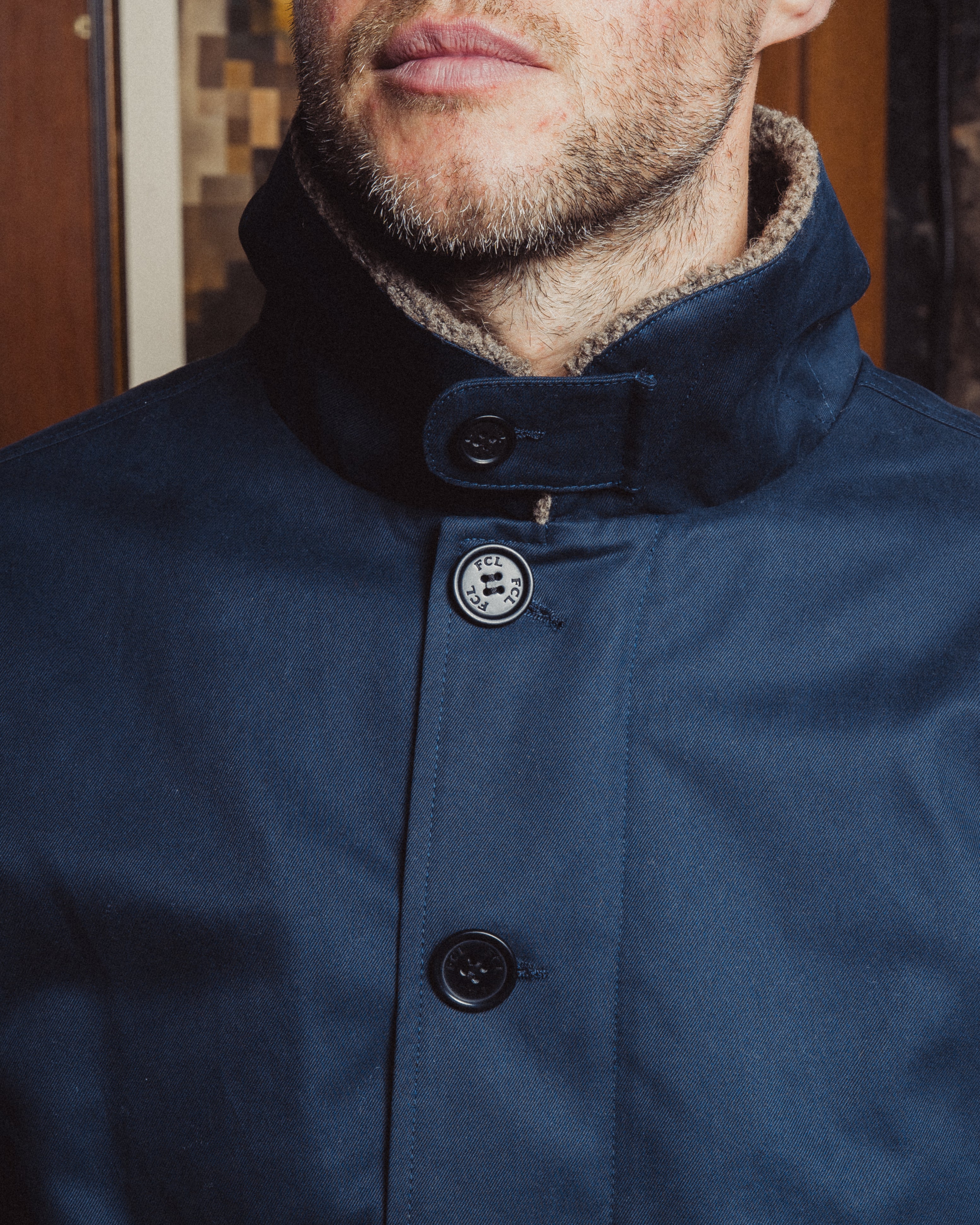 Close-up of a blue coat with buttons, focusing on the collar and buttons.