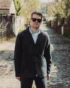 Man wearing sunglasses and a dark jacket on a cobblestone street