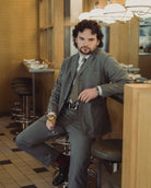 Man in a suit holding a glass of wine in a restaurant setting
