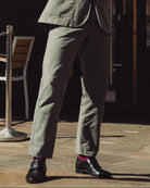 Man in a suit standing outside a corner shop with tables and chairs.