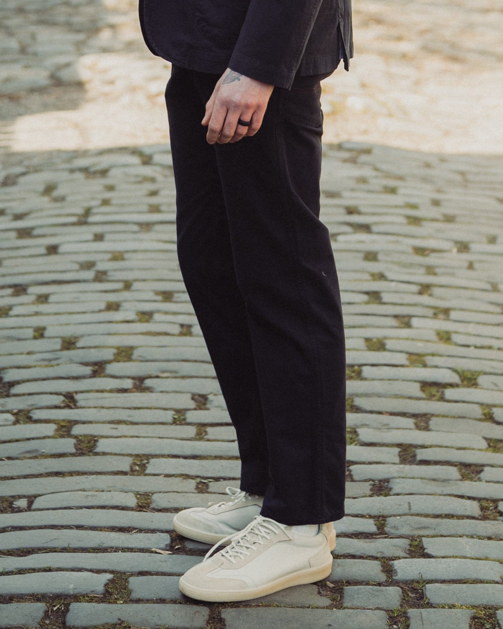 Man in a dark suit and sunglasses standing on a cobblestone street.