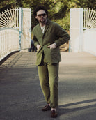 Man in a green suit standing on a bridge with white railings.