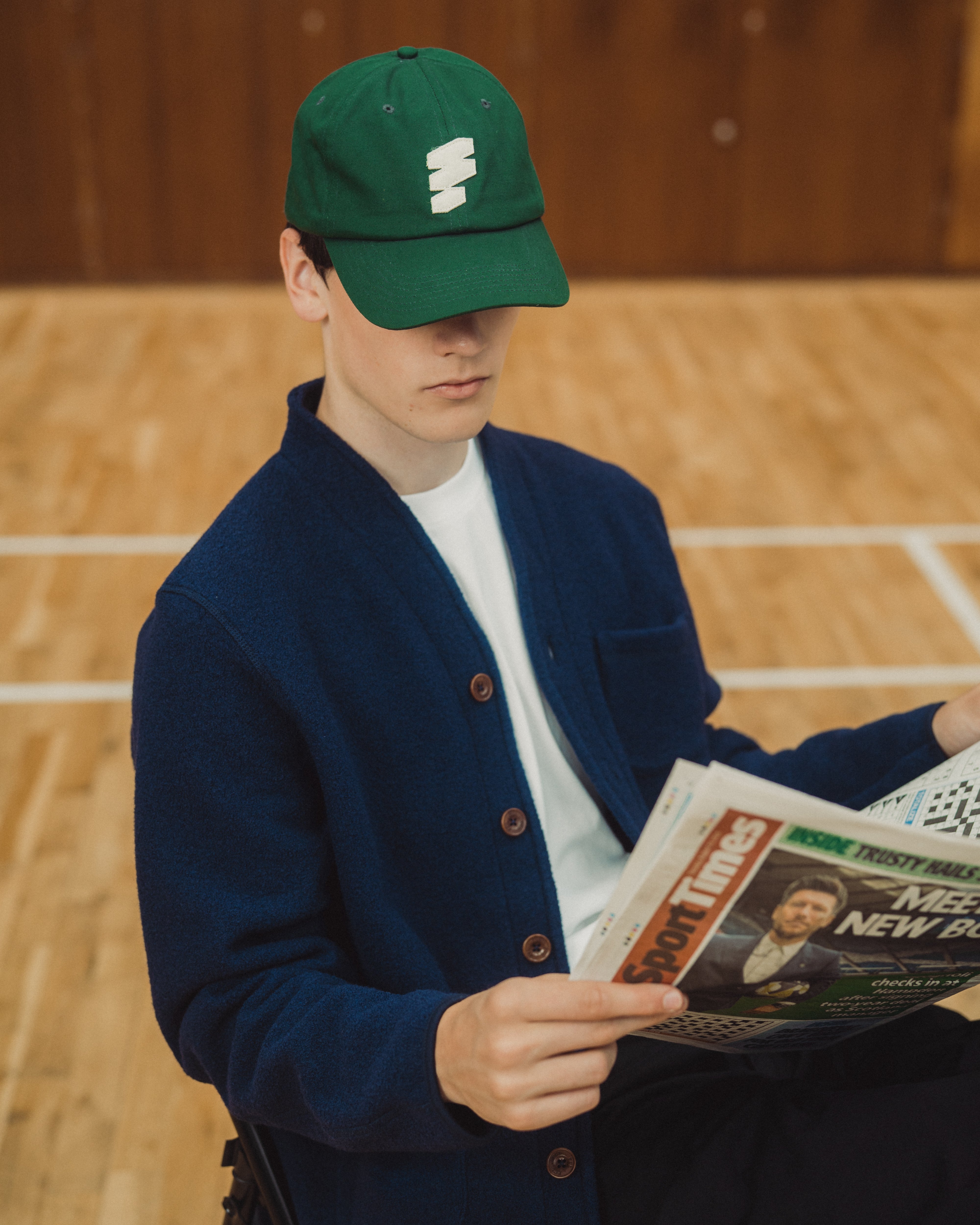 man sitting in wool cardiagn , reading news paper