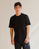 Person wearing a black t-shirt against a plain background