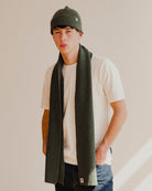 Person wearing a green beanie plain white t-shirt and scarf with a plain background