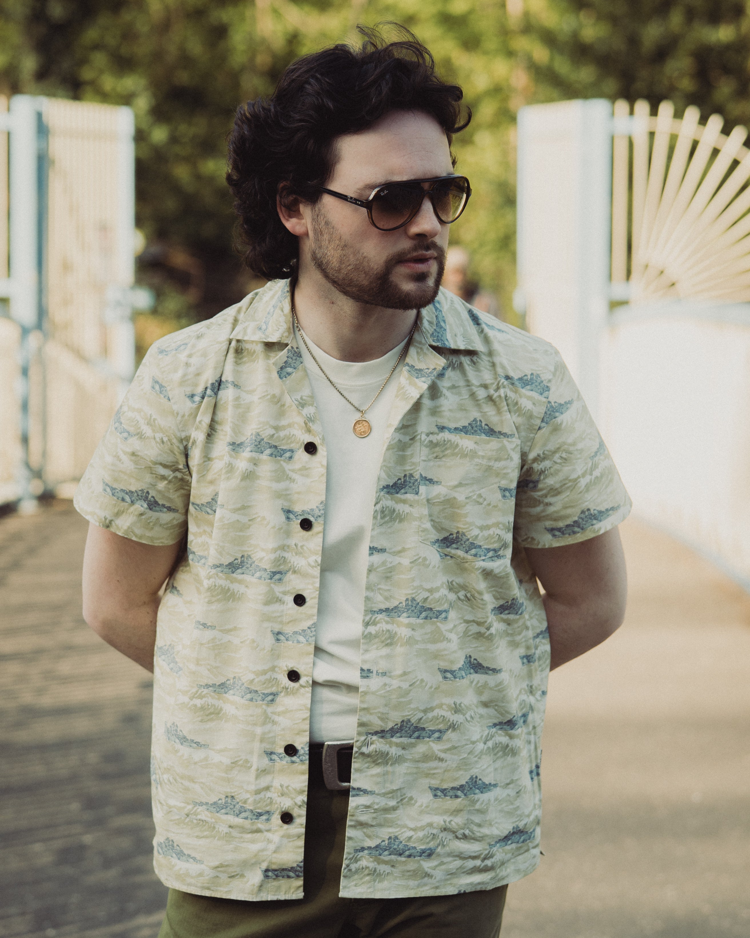 Man wearing a patterned shirt and sunglasses outdoors